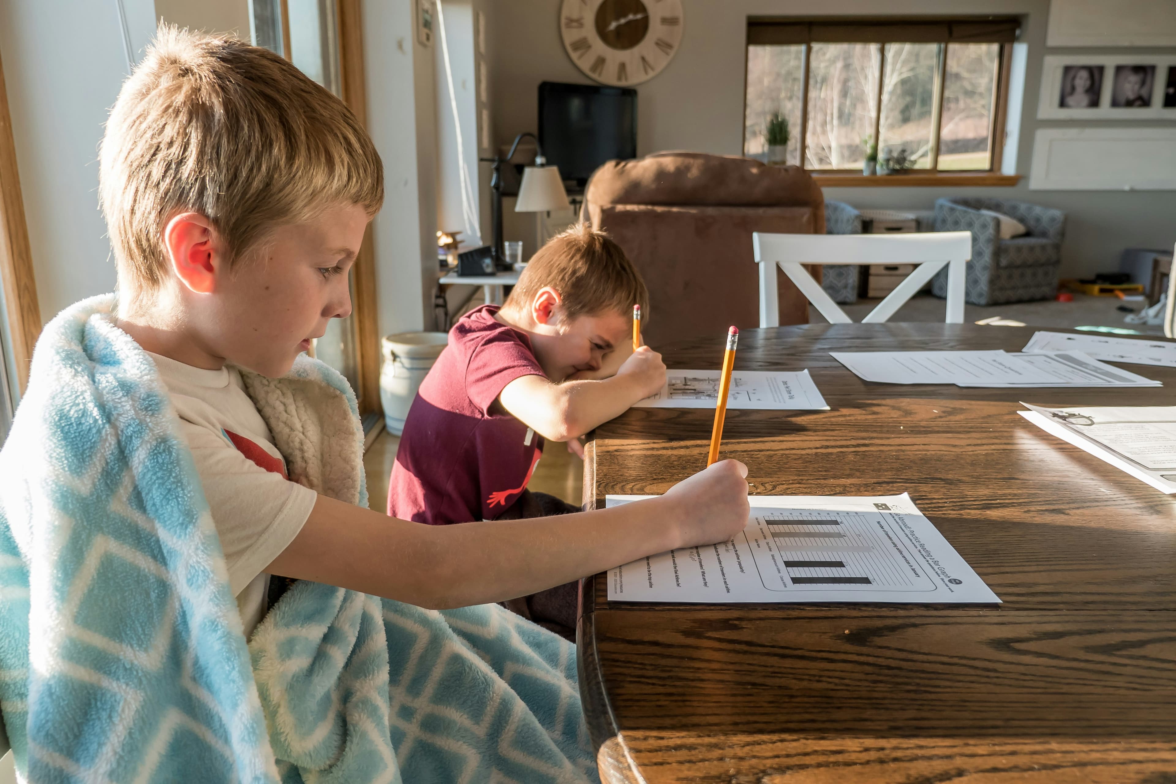 Two children doing schoolwork at a table at home